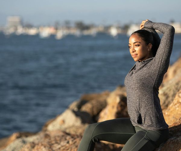 Person stretching joyfully outdoors against a sunrise background.