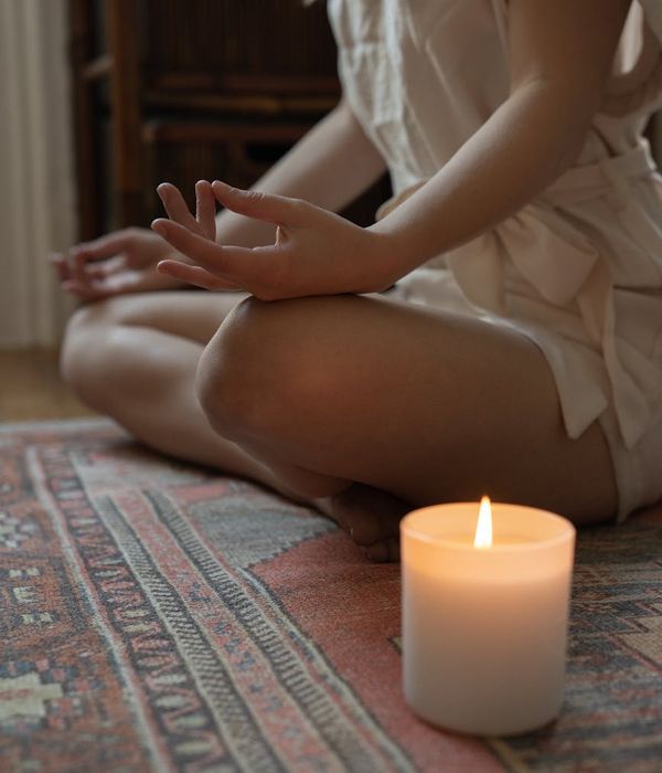 Woman sitting in a calm meditation pose with soft ambient light.